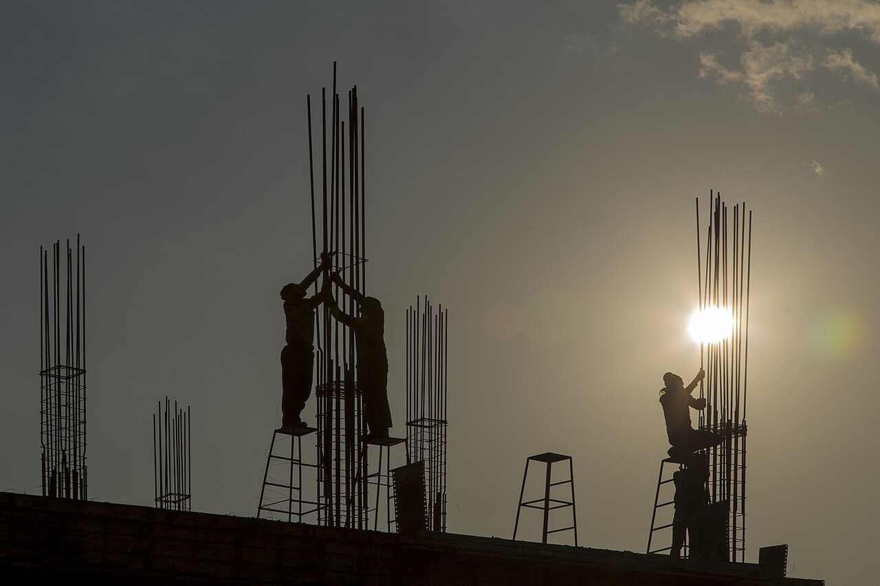 Ouvriers montant la structure d'un bâtiment au soleil couchant